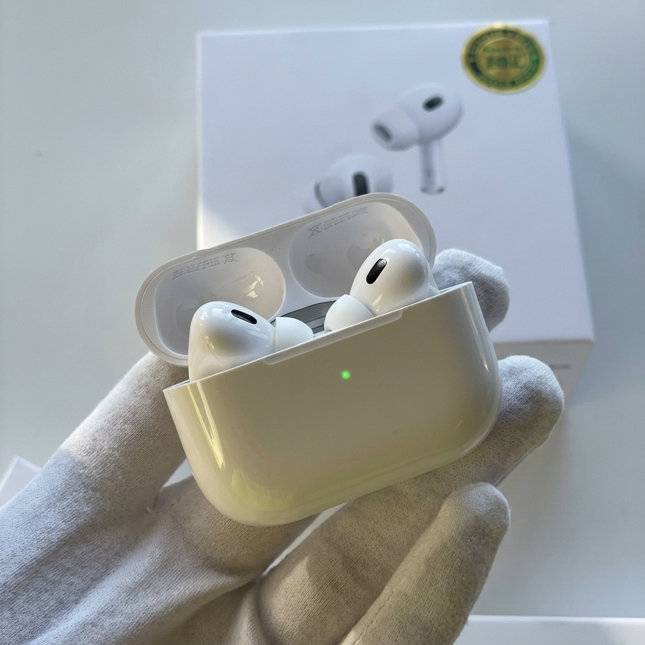 A hand wearing a white glove holds an open white wireless earbud charging case with two earbuds inside. A white product box with a gold circular sticker is visible in the background.