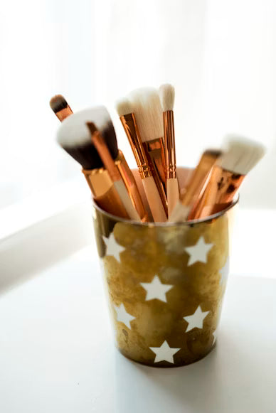 Makeup brushes in a cup with star patterns on a white background